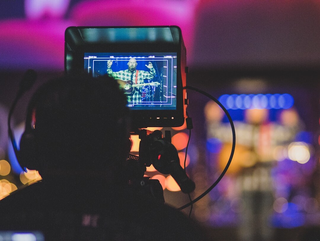 Camera operator filming a live concert event with a broadcast television camera